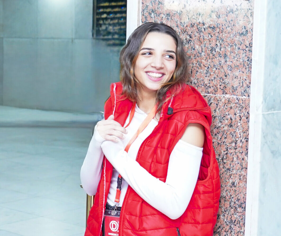 Designott usher smiling in red vest at a managed event