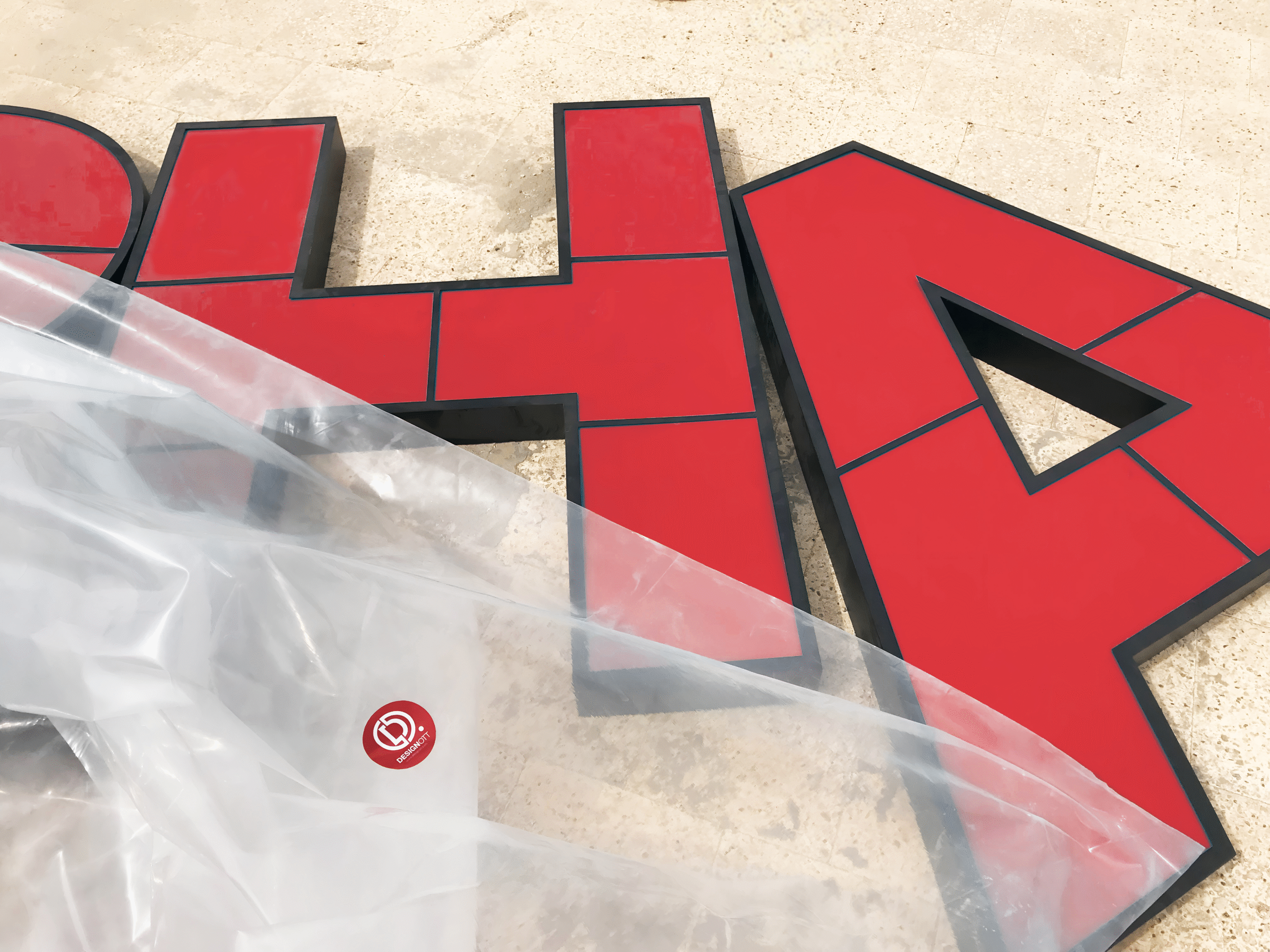Red cladding and stainless steel signage partially wrapped with Designott sticker