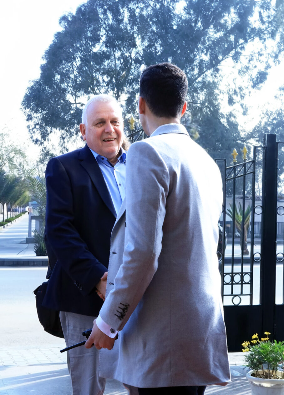 Designott supervisor welcoming international guests during a conference.